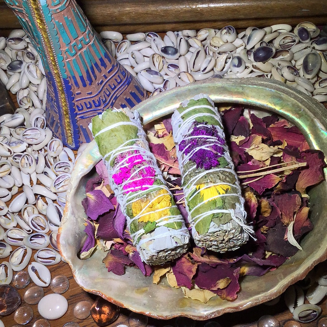 A four inch bundle of white sage and yellow, red, or purple flowers within.