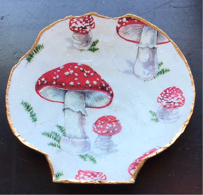 A clamshell with amanita mushrooms painted on its inside. Gold leaf edge. Perfect for holding rings or magical trinkets!