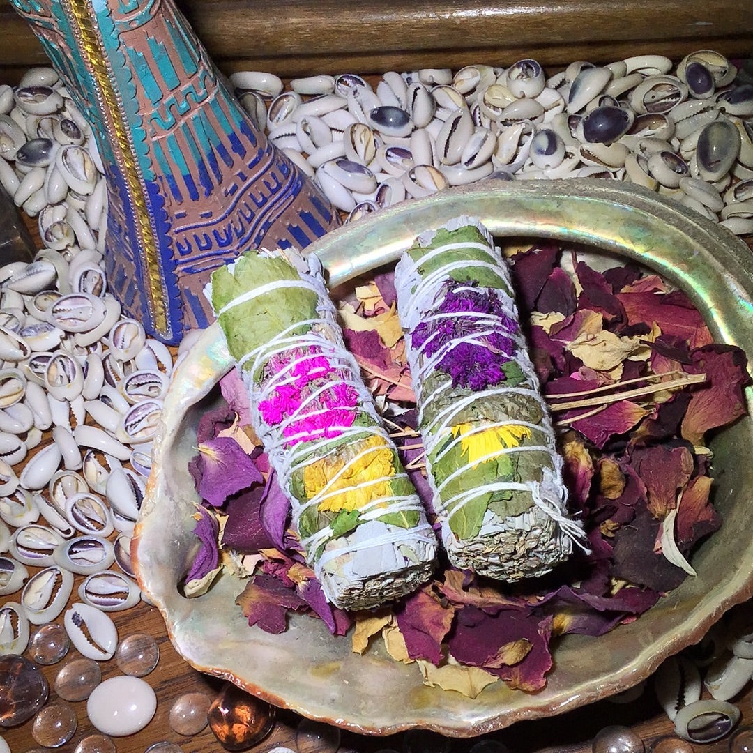 A four inch bundle of white sage and yellow, red, or purple flowers within. 